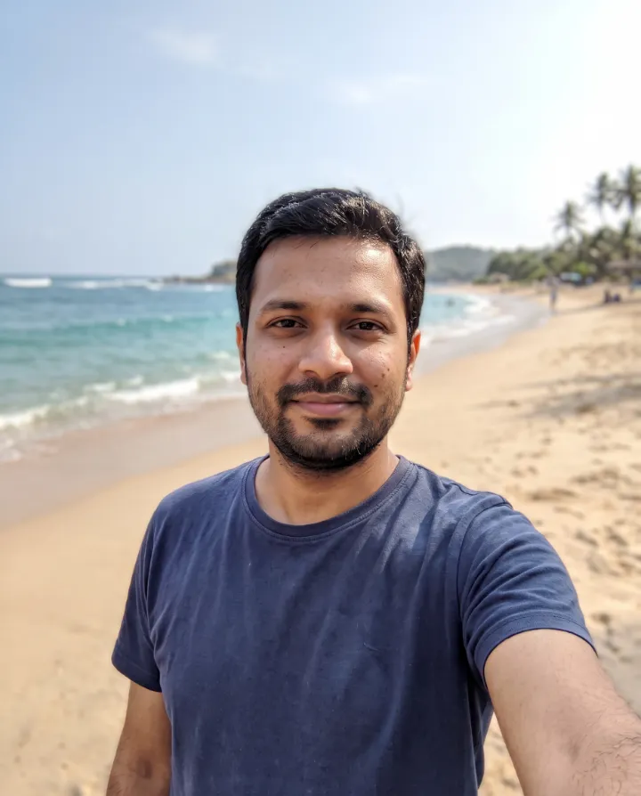 The same man with the street behind him replaced by a sunny beach with turquoise water