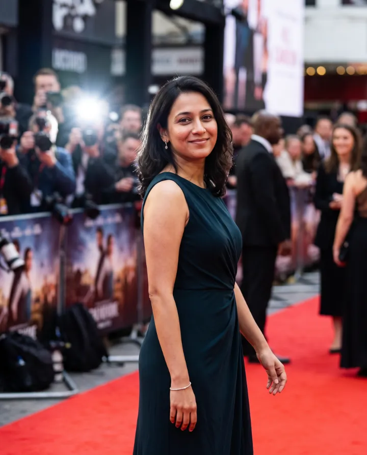 AI red-carpet glamour photo of the same woman in a dark green dress with photographers behind her