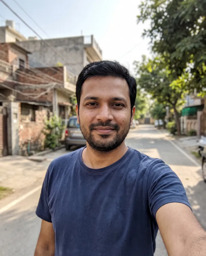 Casual selfie of a bearded man in a navy t-shirt on a quiet street (an AI-generated person)